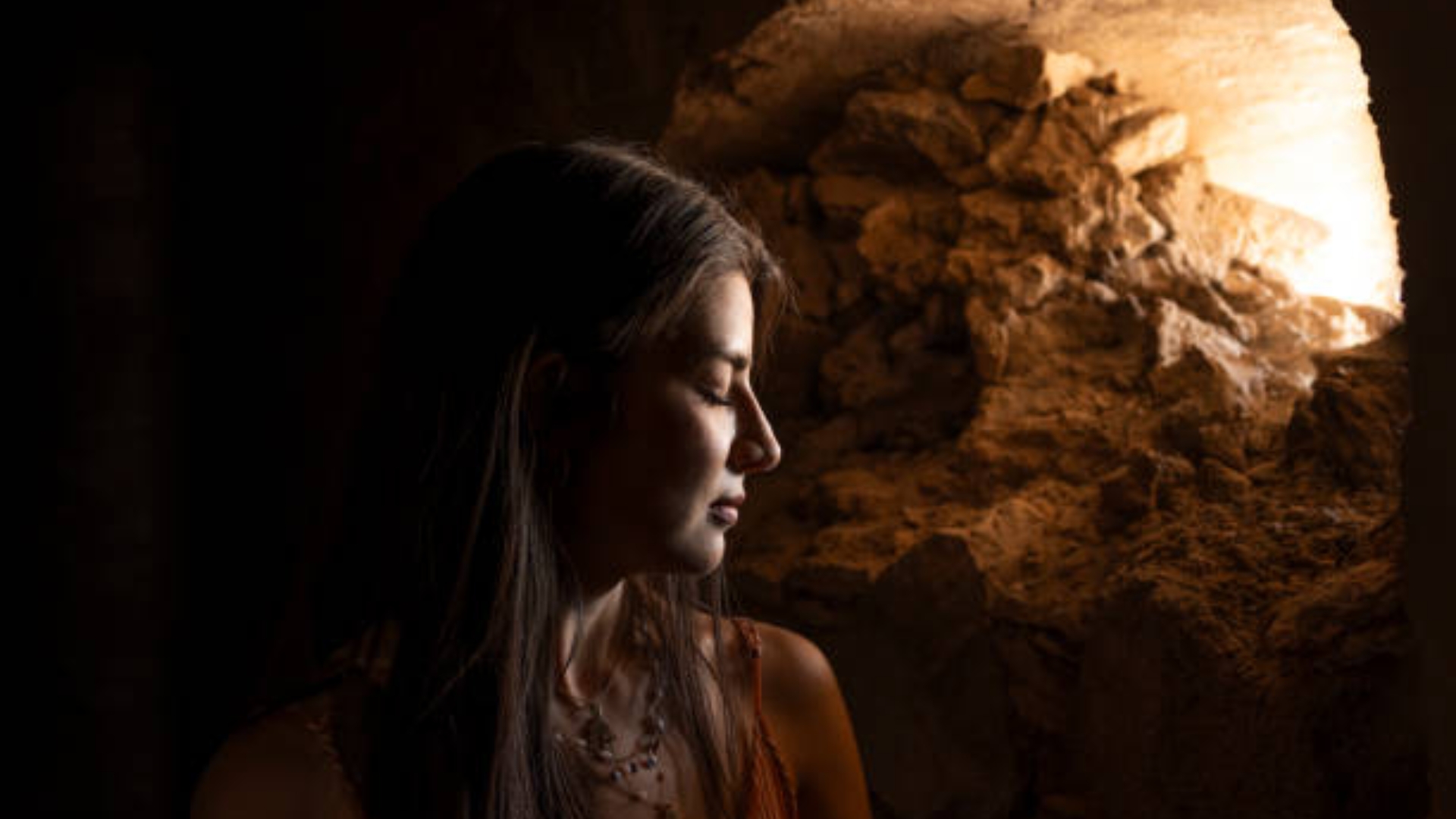 Silhouetted person facing inner light with emotional symbols, representing shadow work and self-inquiry